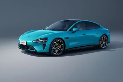 Tampak samping depan mobil listrik terbaru Xiaomi SU7 berwarna biru yang sedang melaju di jalan raya aerodinamis.